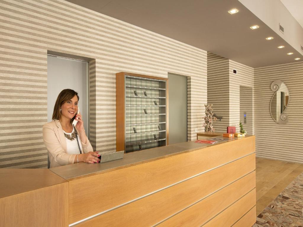 une femme qui parle sur un téléphone portable à un comptoir dans l'établissement Hotel Pillon, à Bibione 118 autres photos