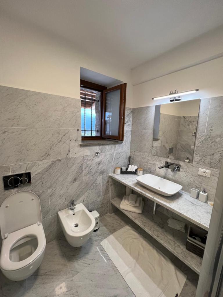une salle de bain avec toilettes, lavabo et miroir dans l'établissement Villa Podere Vista Verde, à Castel del Piano