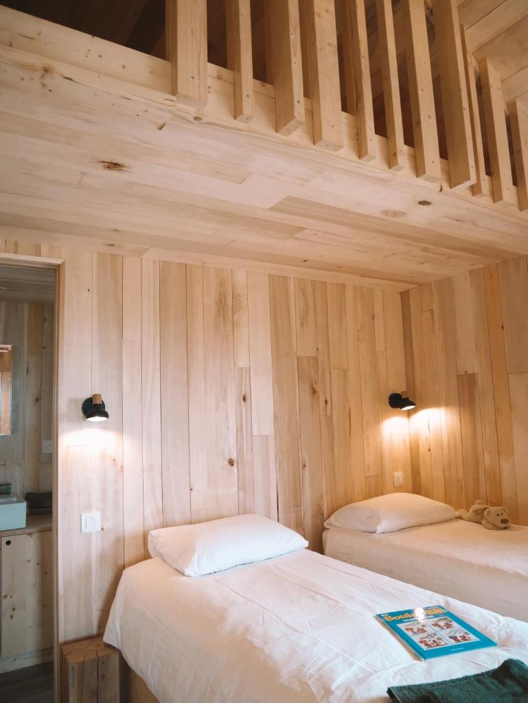 deux lits dans une chambre aux murs en bois dans l'établissement Domaine St-Amand, à Saint-Amand-de-Coly