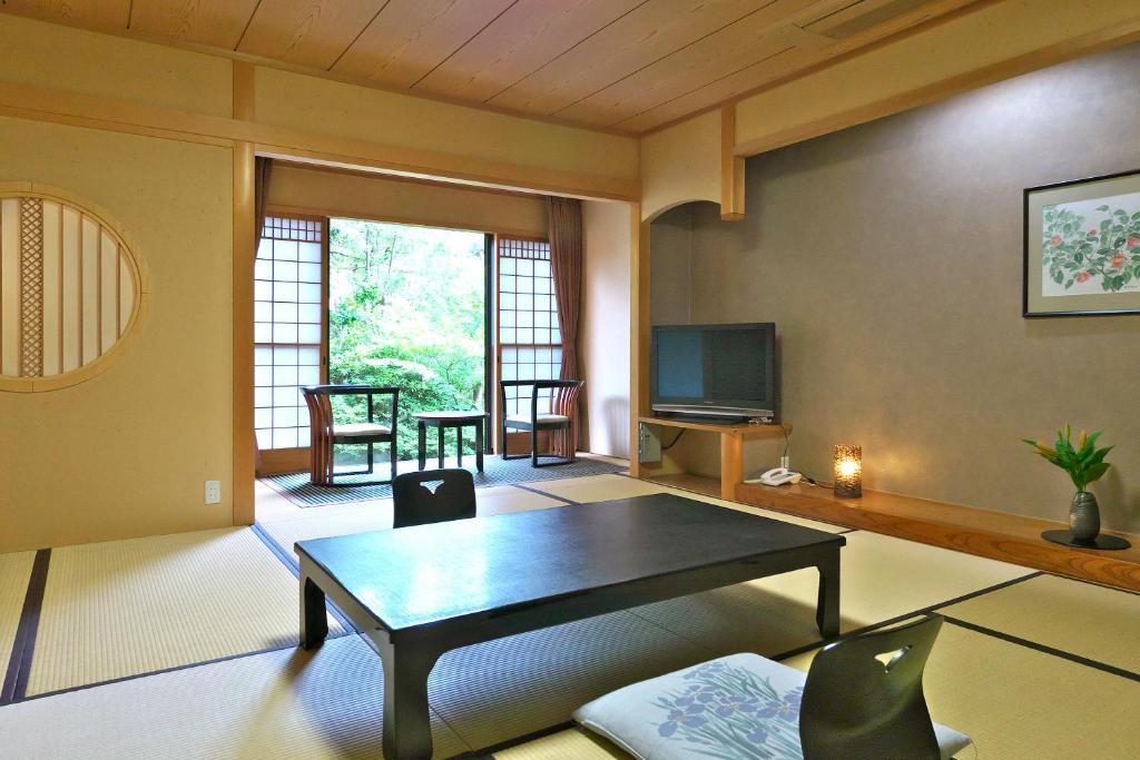 un salon avec une table et une télévision dans l'établissement Yuraku Hotel, à Awara