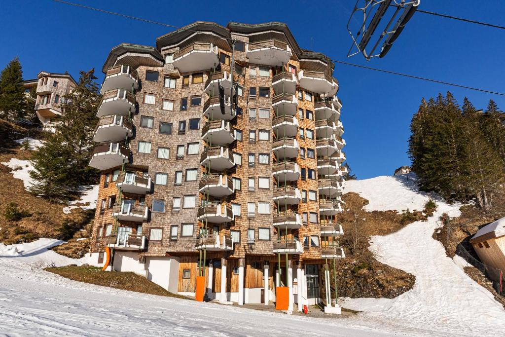 un grand bâtiment sur une piste enneigée avec une remontée mécanique dans l'établissement Chalet Choucas by Avoriaz Chalets, à Avoriaz