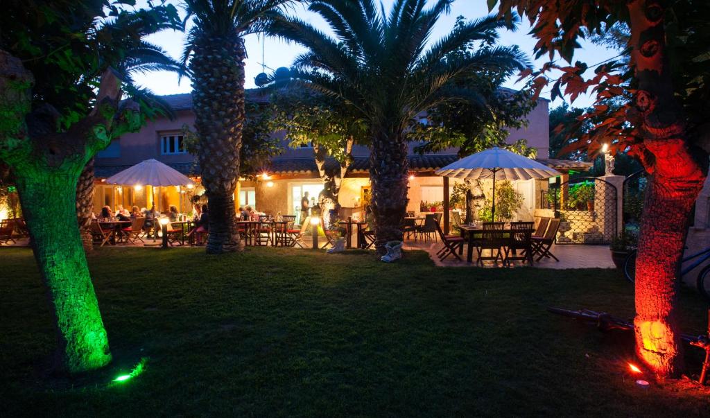 - un jardin avec des tables et des palmiers la nuit dans l'établissement Camping Resort Les Champs Blancs, à Agde