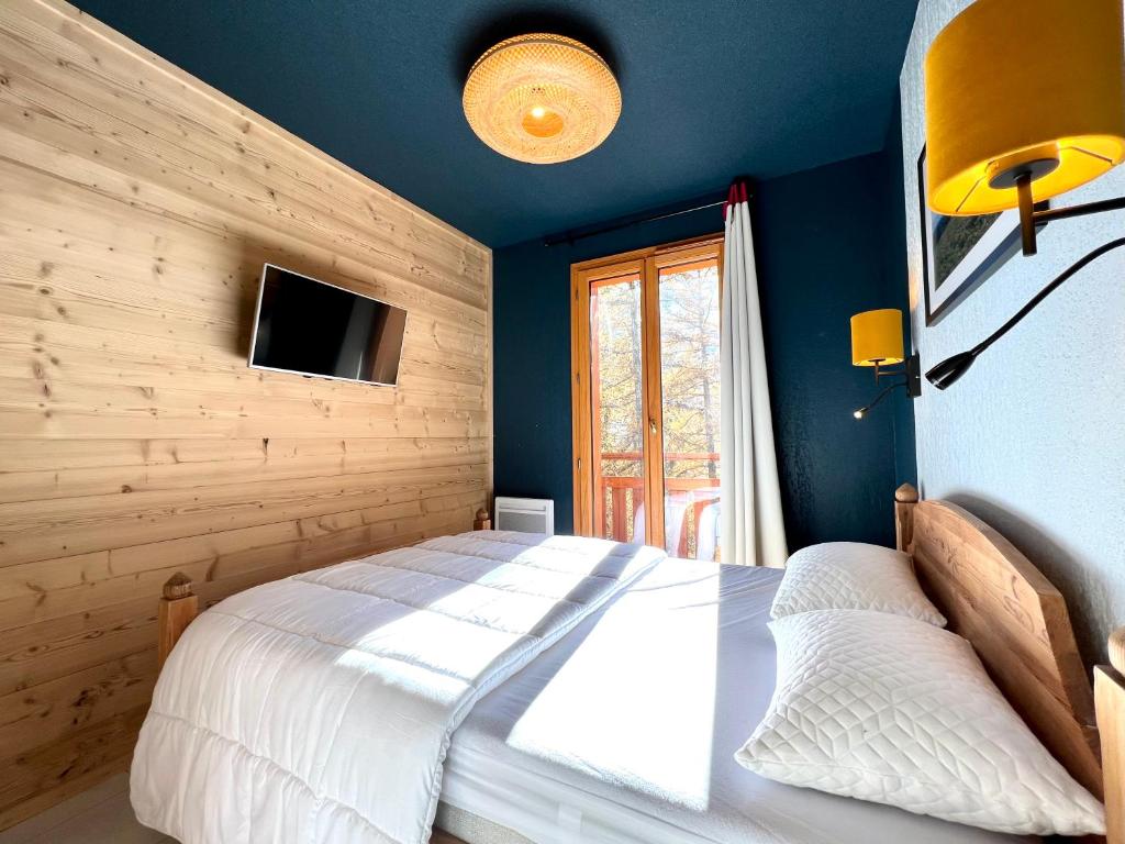 une chambre avec un lit et une télévision sur un mur dans l'établissement CENTRE STATION 1800 - Dernier étage Rénové - 2 Chambres 6 personnes - Skis aux pieds, aux Orres