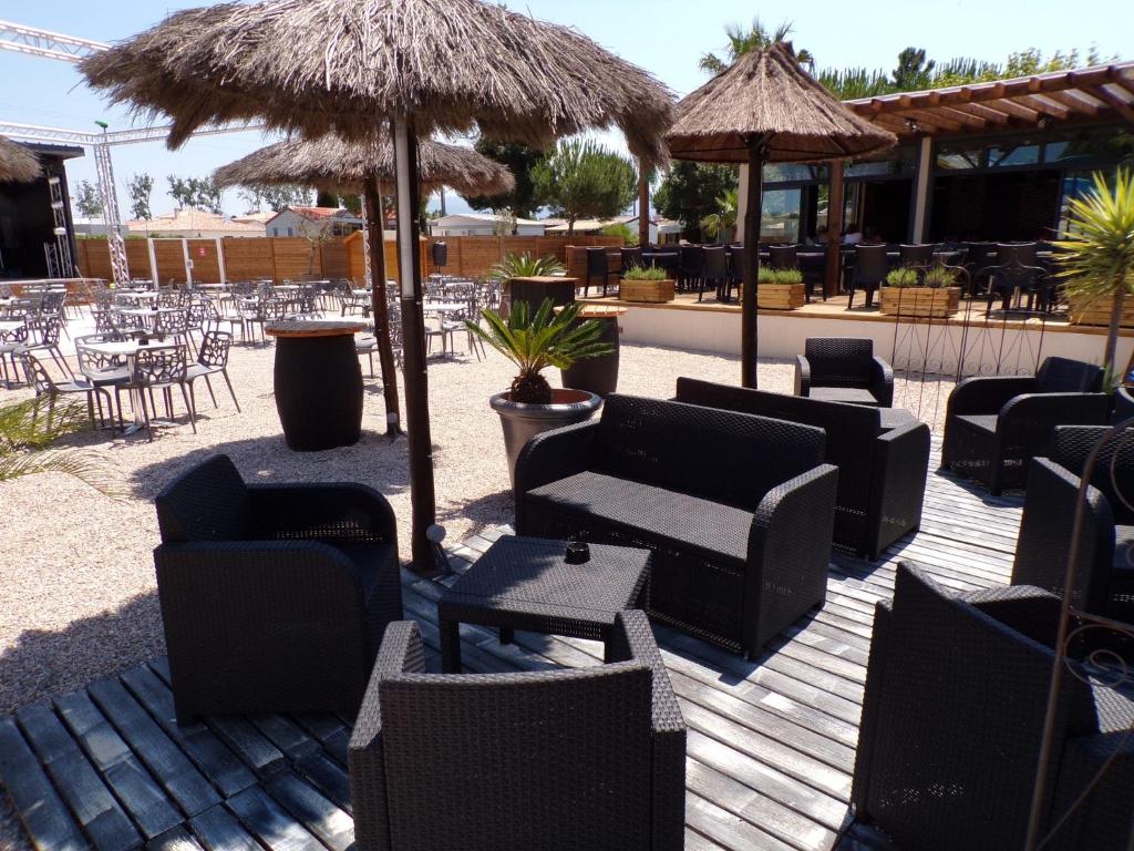 une terrasse avec des chaises, des tables et des parasols dans l'établissement Sun Sea camping le Bosc, à Saint-Cyprien