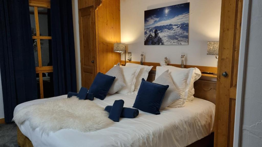 une chambre avec un lit avec des oreillers bleus et blancs dans l'établissement Arc 1950 Appartement de standing Refuge du Montagnard, vue incroyable sur le Montblanc, skis aux pieds Accès spa et piscine, à Arc 1950