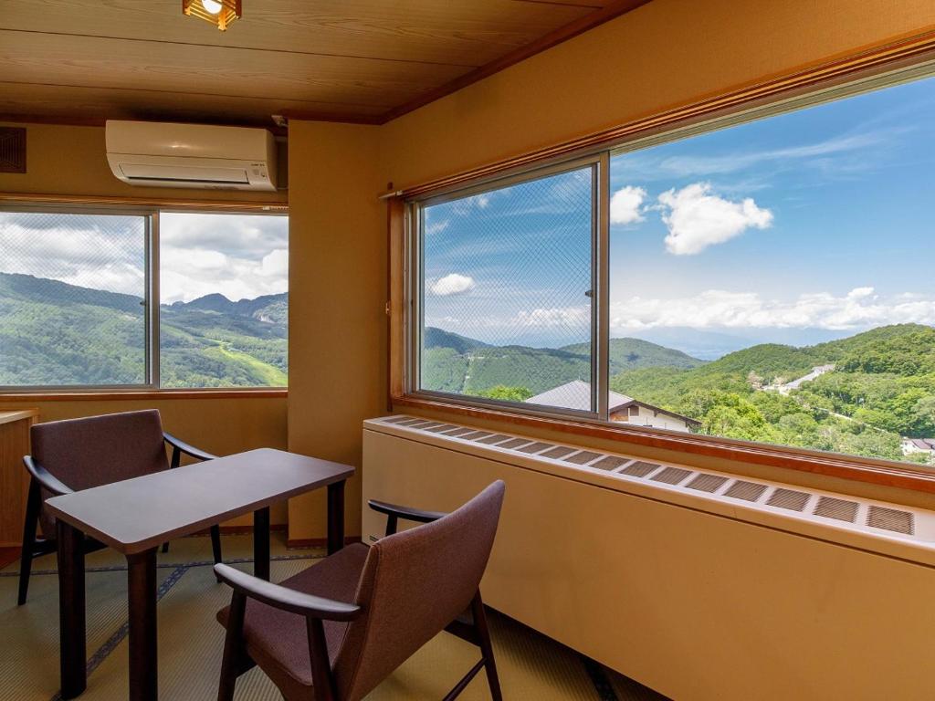 une pièce avec une table et des chaises et une grande fenêtre dans l'établissement Hotel Iwasuge, à Yamanouchi 50 autres photos