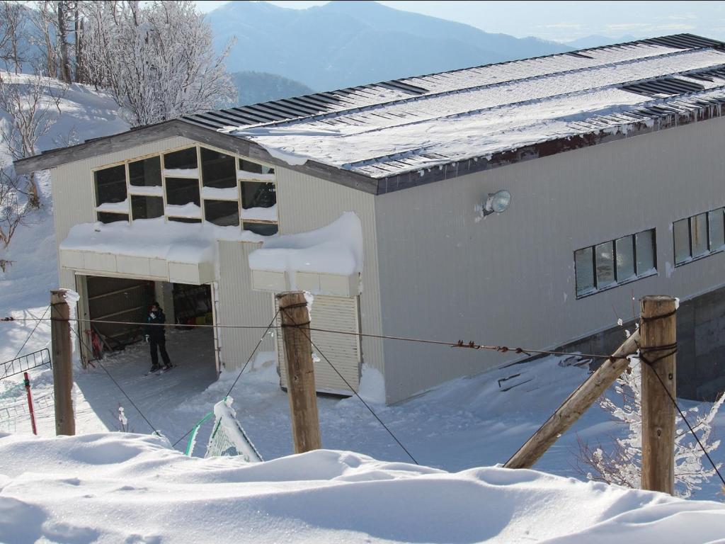 une maison dans la neige avec une personne debout à l'extérieur dans l'établissement Hotel Iwasuge, à Yamanouchi