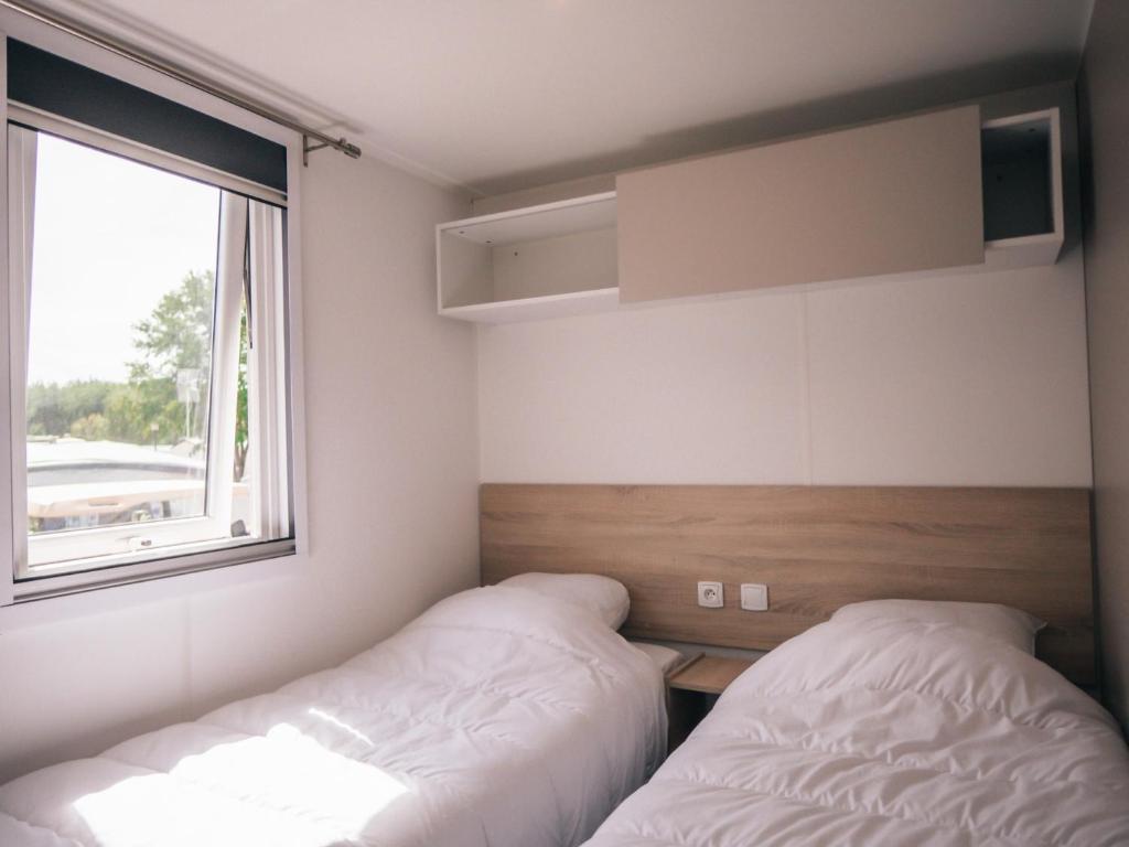 une chambre avec deux lits et une fenêtre dans l'établissement Camping Les Jardins de la Mer, à Merlimont 36 autres photos