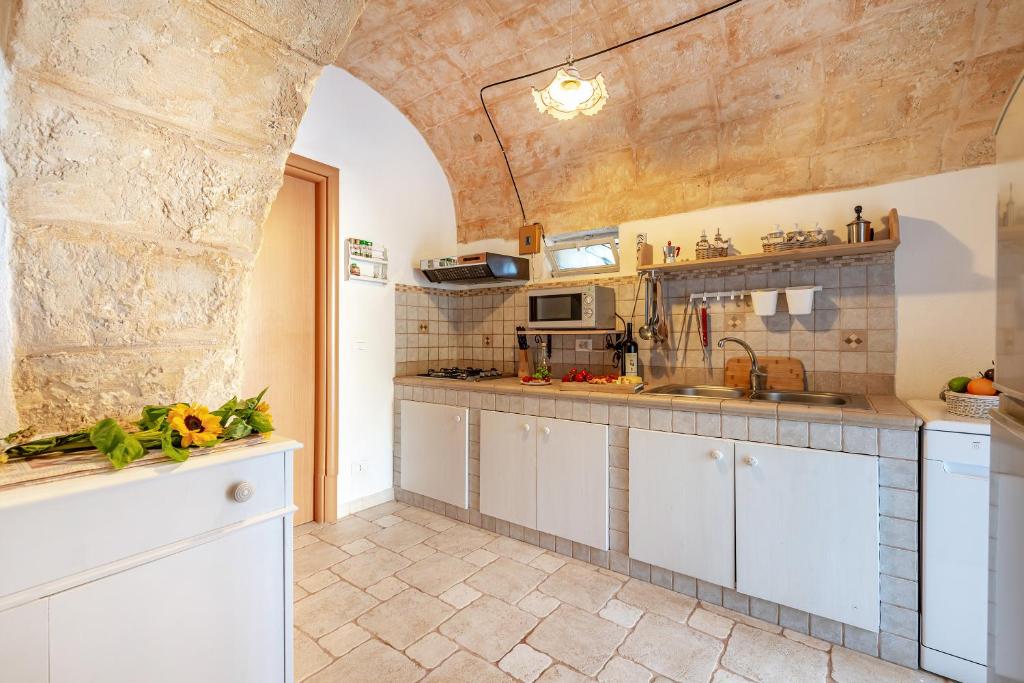 - une cuisine avec des placards blancs et un mur en pierre dans l'établissement Trullo Delle Ginestre Private Pool - Happy Rentals, à Latiano