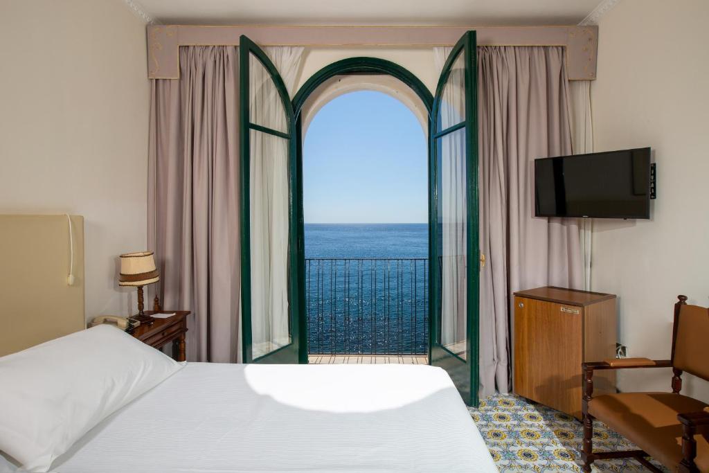 une chambre avec un lit et une vue sur l'océan dans l'établissement Hotel Lido Mediterranee, à Taormine