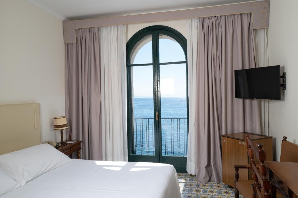 une chambre d'hôtel avec un lit et une grande fenêtre dans l'établissement Hotel Lido Mediterranee, à Taormine