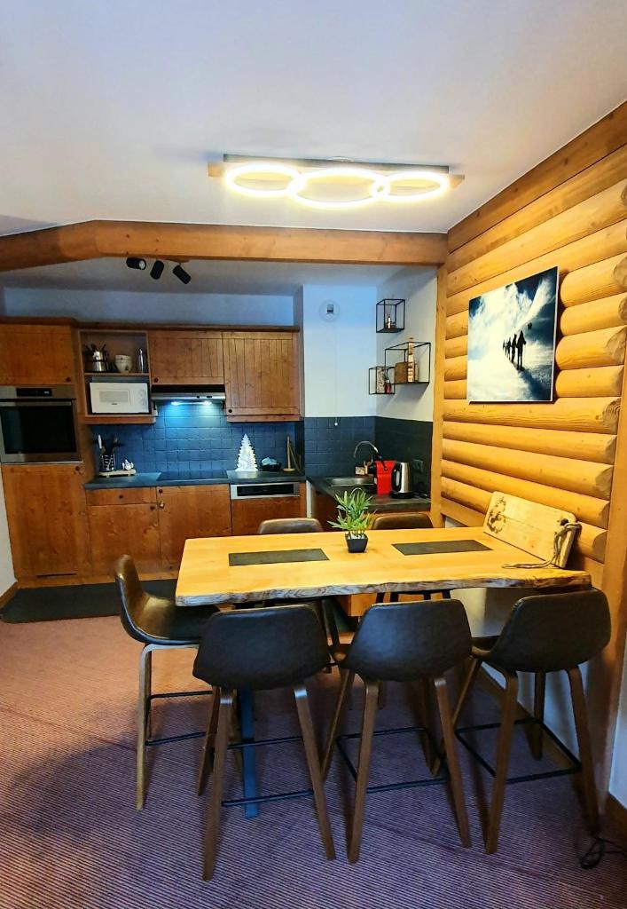 une cuisine avec une table en bois et quelques chaises dans l'établissement Appartement ARC 1950 m, Ski au pied, piscine extérieure chauffée, remontées mécaniques à 100m, sauna et salle de sports, à Arc 1950
