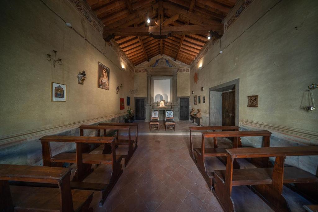 une chambre avec des tables et des bancs en bois dans un bâtiment dans l'établissement Fattoria di Piantravigne Villa Storica del 600, à Case Malva