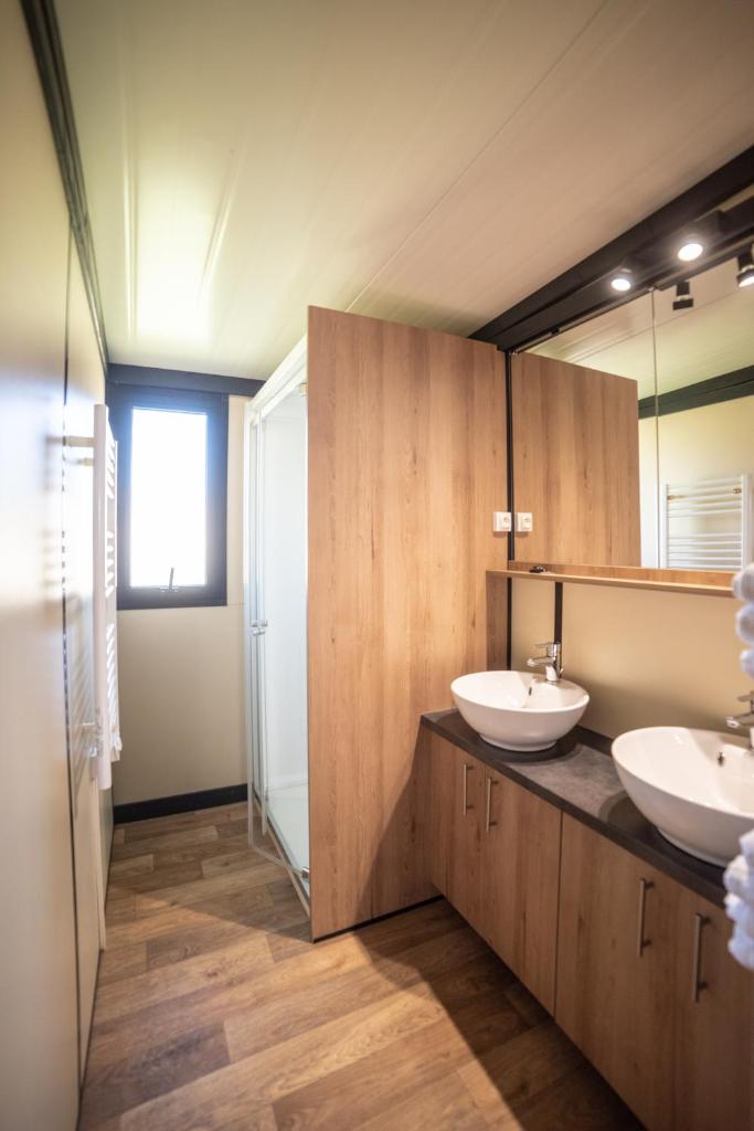 une salle de bain avec deux lavabos et un miroir dans l'établissement Camping du Sevron, à Saint-Étienne-du-Bois