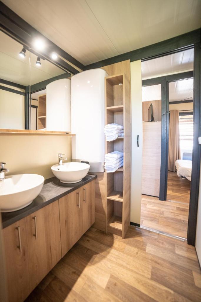 une salle de bain avec deux lavabos et un grand miroir dans l'établissement Camping du Sevron, à Saint-Étienne-du-Bois