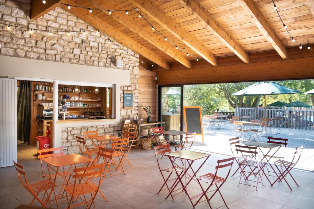 un patio avec tables et chaises dans un bâtiment dans l'établissement Huttopia Lac de Serre-Ponçon, à Le Lautaret