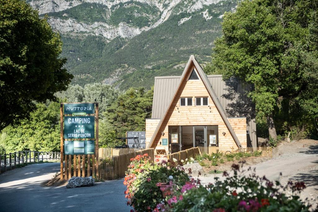 un petit bâtiment avec un panneau en face d'une montagne dans l'établissement Huttopia Lac de Serre-Ponçon, à Le Lautaret 17 autres photos