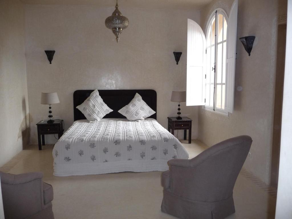 une chambre avec un lit blanc et deux chaises dans l'établissement Palais Villa Talaa Resort, à Taroudant