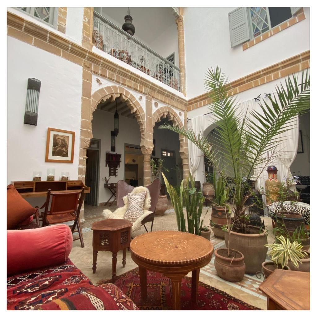 un salon rempli de nombreuses plantes et tables dans l'établissement Riad le Consulat - Private Riad, Breakfast included, à Essaouira