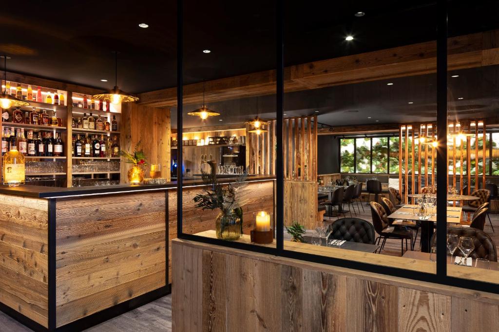 un restaurant avec des murs en bois et un bar dans l'établissement Hôtel et Spa Le Vermont, au Grand-Bornand