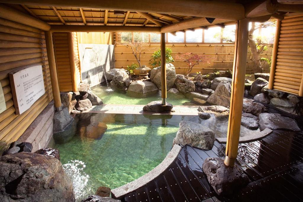 une grande piscine d'eau avec des rochers dans un bâtiment dans l'établissement Hotel Meizanso, à Gamagori 37 autres photos