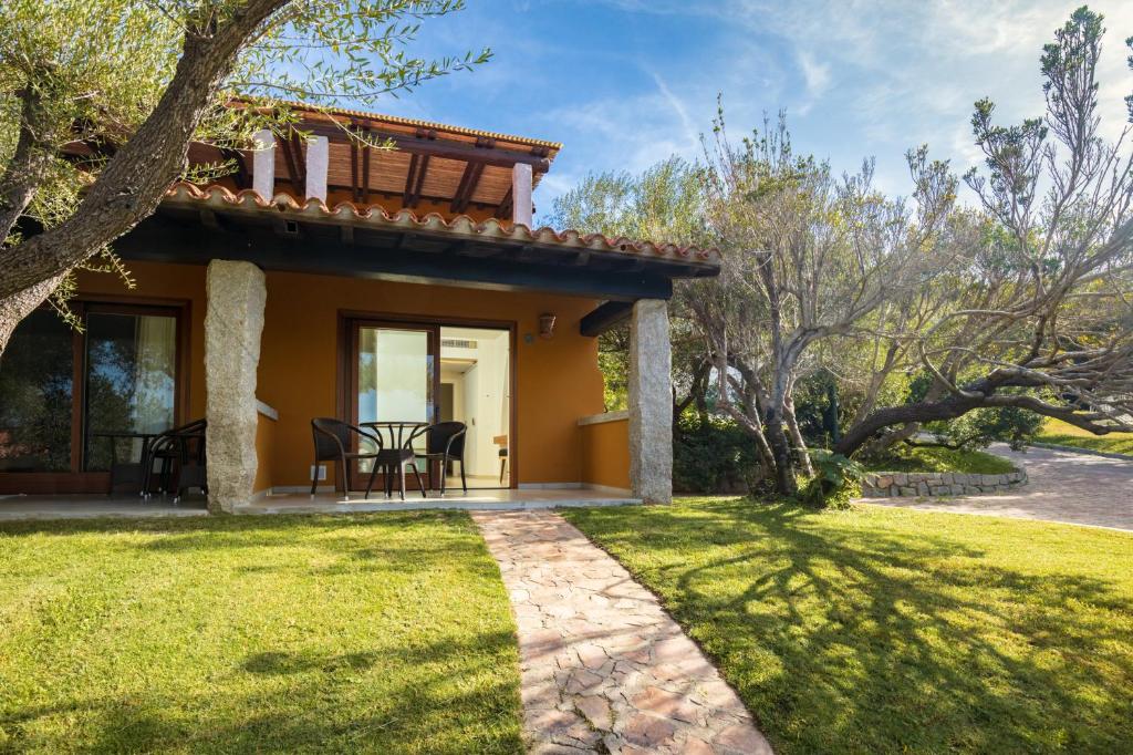 une maison avec une terrasse et une pelouse dans l'établissement Hotel Club Saraceno - Bovis Hotels, à Àrbatax