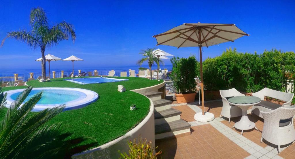 une piscine avec un parasol, une table et des chaises dans l'établissement Hotel Residence Piccolo, à Parghelia