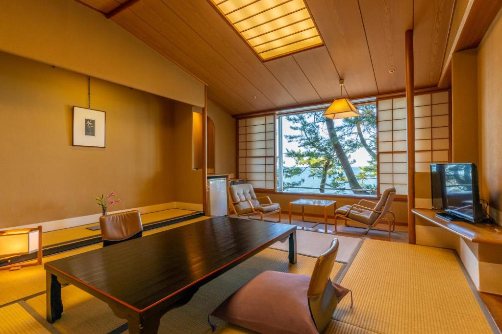 une pièce avec une table, des chaises et une fenêtre dans l'établissement Kasuitei, à Yonago