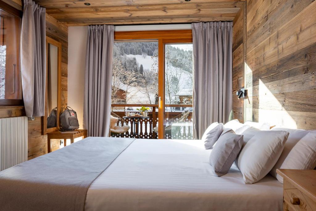 une chambre avec un grand lit et une grande fenêtre dans l'établissement Hôtel et Spa Le Vermont, au Grand-Bornand