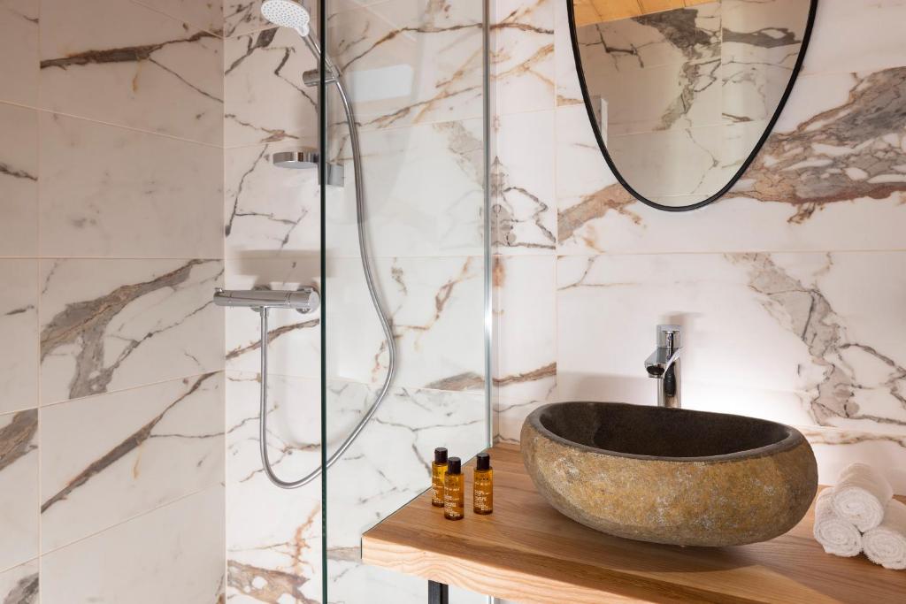 une salle de bain avec un lavabo en pierre et une douche dans l'établissement Hôtel et Spa Le Vermont, au Grand-Bornand