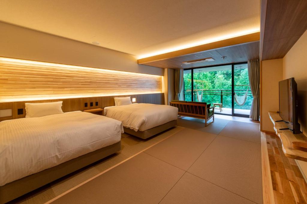 une chambre d'hôtel avec deux lits et une télévision dans l'établissement Sakunami Onsen Yuzukushi Salon Ichinobo, à Sendai