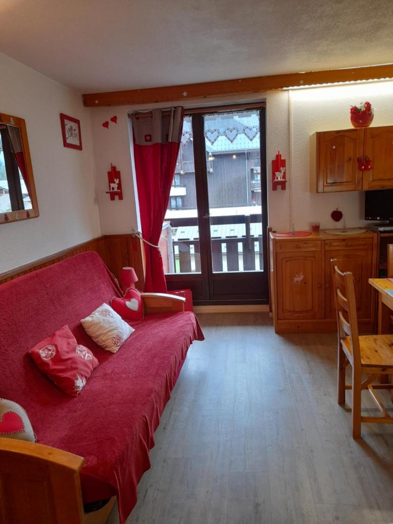 un salon avec un canapé rouge et une cuisine dans l'établissement Samoëns studio, à Samoëns