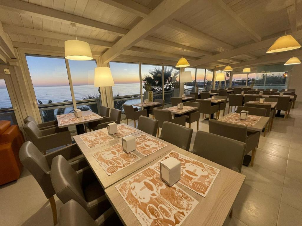 un restaurant avec des tables et des chaises et une vue sur l'océan dans l'établissement Hotel Sul Mare Al Gabbiano, à Scoglitti