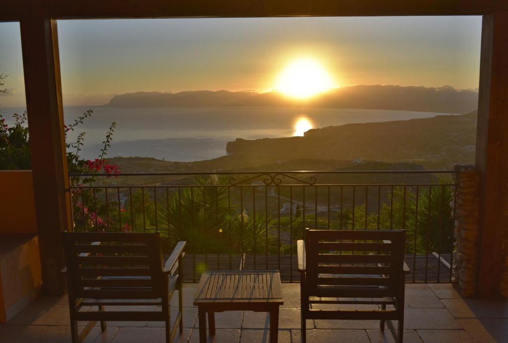 d'une table et de chaises sur un balcon avec vue sur le coucher du soleil. dans l'établissement Villa Fenice, à Scopello