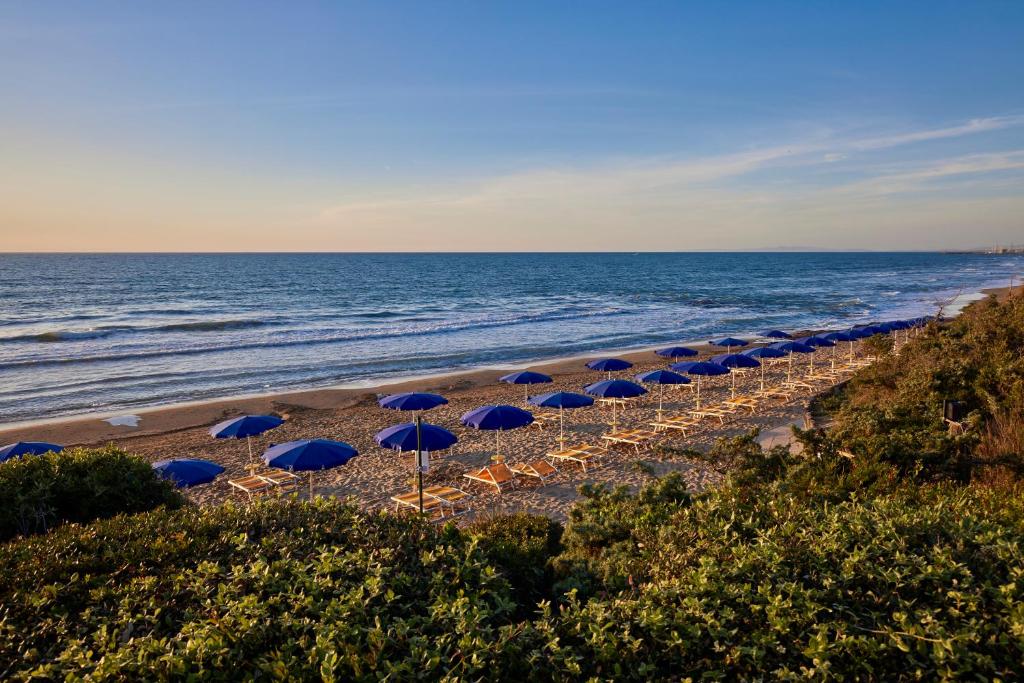 une ligne de parasols sur une plage avec l'océan dans l'établissement Park Hotel I Lecci, à San Vincenzo