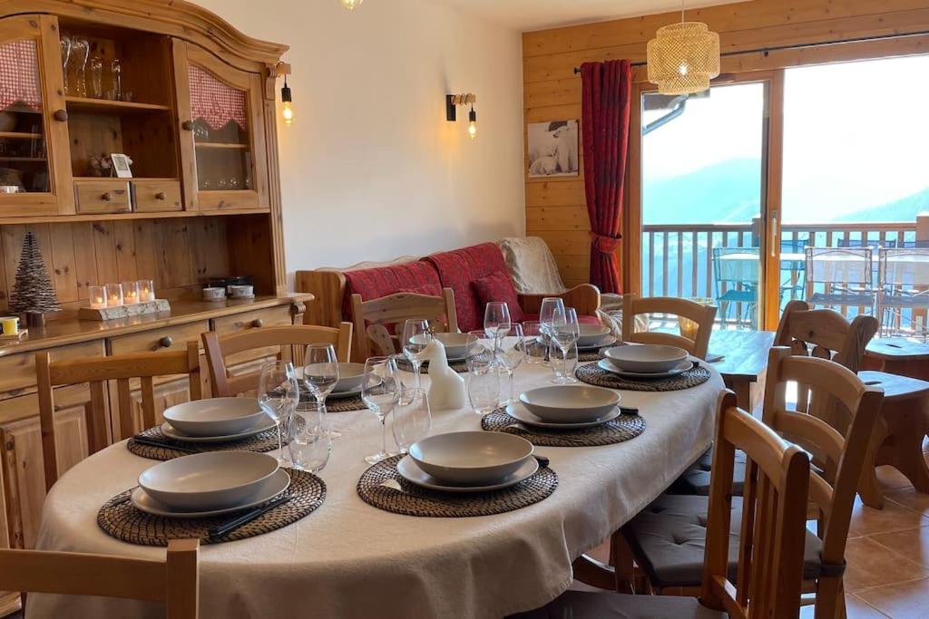 une salle à manger avec une table avec des assiettes et des verres à vin dans l'établissement La Perle des Alpes C10 Apart.4* #Yolo Alp Home, à Villard-sur-Doron