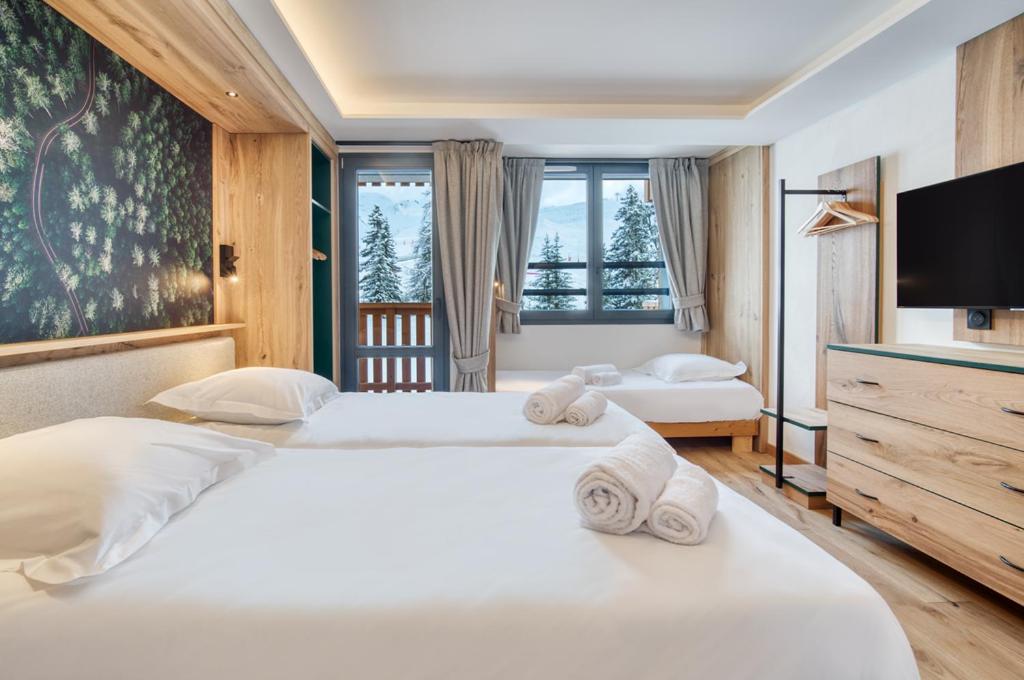 une chambre avec deux lits et une télévision à écran plat dans l'établissement Chalet Hôtel Turquoise, à La Plagne Tarentaise