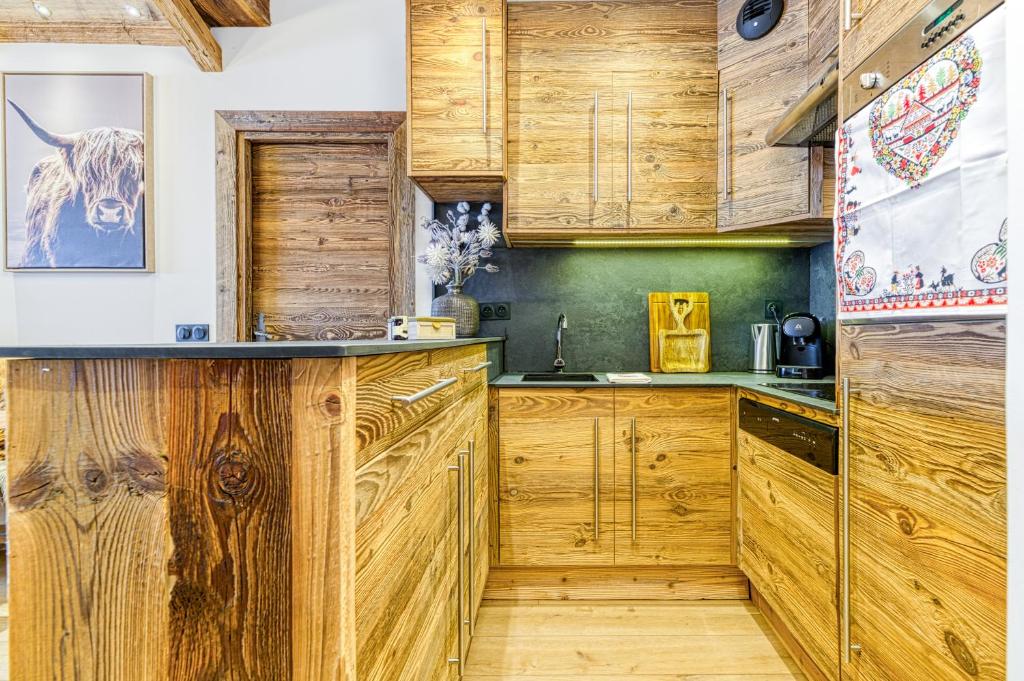 une cuisine avec des placards en bois et une vache sur le mur dans l'établissement Appartement style chalet 5* vue Mont-Blanc - Arc 1950, à Arc 1950 16 autres photos