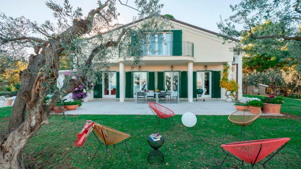 une maison avec des chaises rouges dans la cour dans l'établissement VILLA LUCENTE 6&2, Emma Villas, à Silvi Paese