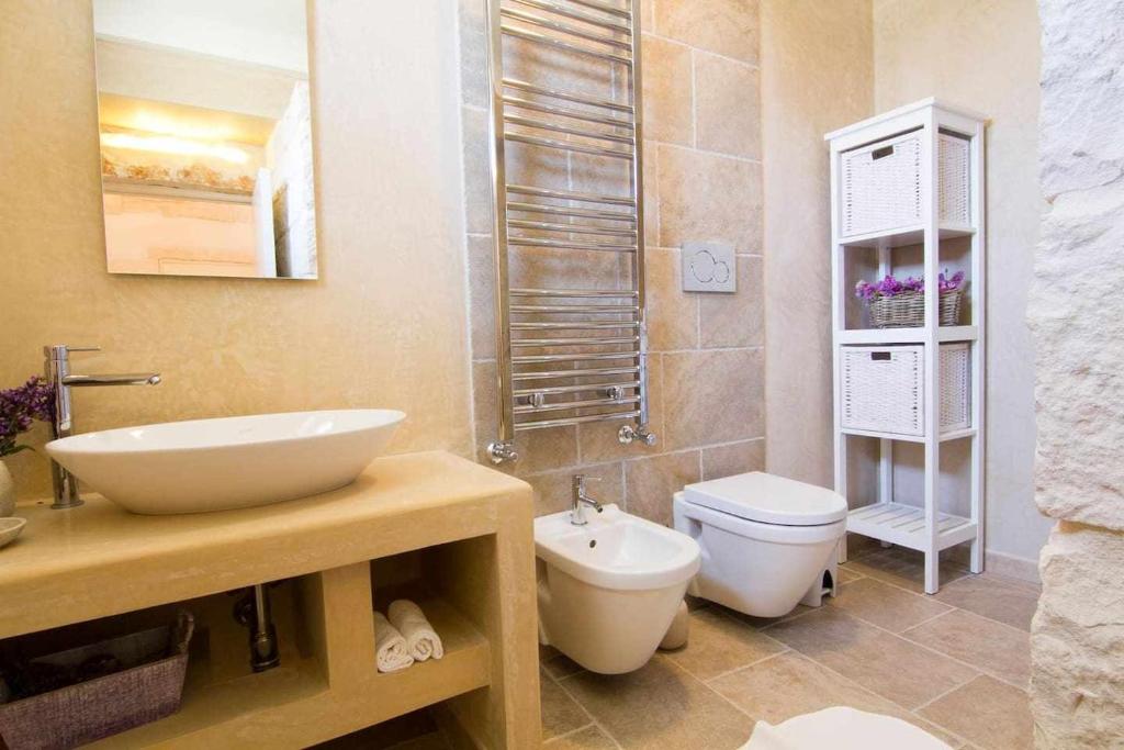 une salle de bain avec un lavabo et des toilettes dans l'établissement Villa Le Nacchere with exclusive pool, à Cisternino