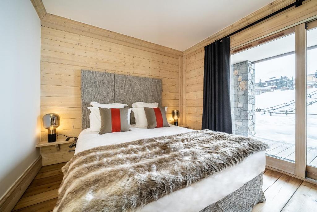 une chambre avec un grand lit et une grande fenêtre dans l'établissement Les Balcons de Pralong Courchevel 1850 - by EMERALD STAY, à Courchevel