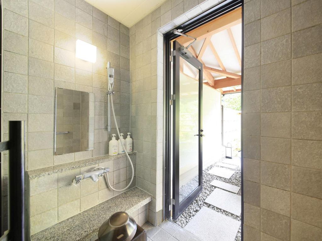 une douche dans une salle de bain avec une porte vitrée dans l'établissement Shimoda Central Hotel, à Shimoda