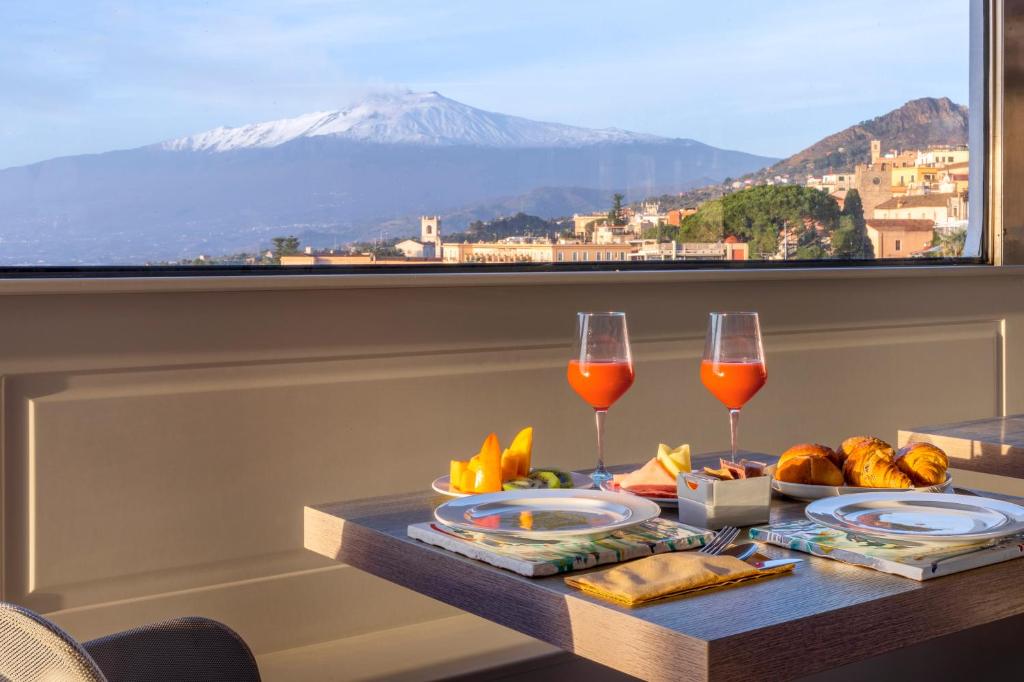 une table avec deux verres de vin et une vue sur une montagne dans l'établissement Hotel Villa Paradiso, à Taormine