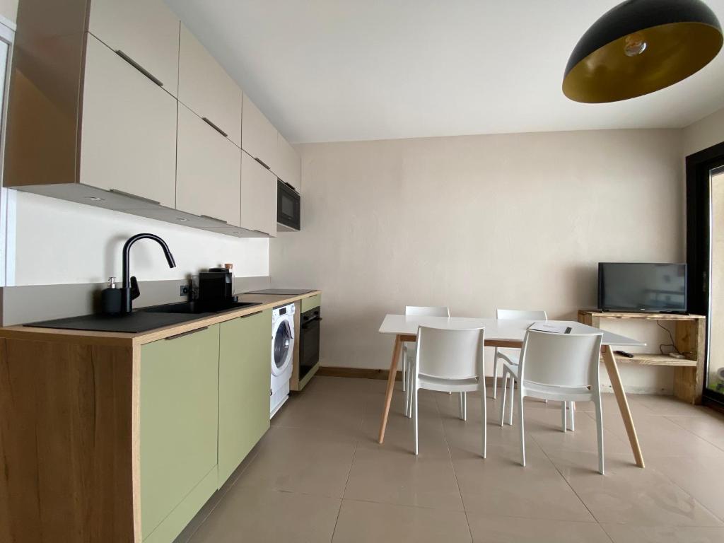 une cuisine avec une table, des chaises et un évier dans l'établissement Le Marlou, à La Toussuire 7 autres photos