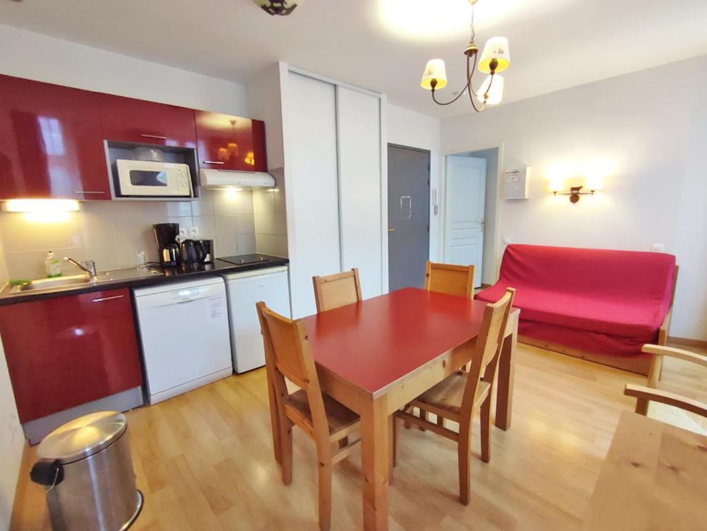 une cuisine et une salle à manger avec une table et des chaises rouges dans l'établissement La petite ourse, T2, centre Luchon, wifi, casier à skis, ascenseur, 4 personnes, à Luchon