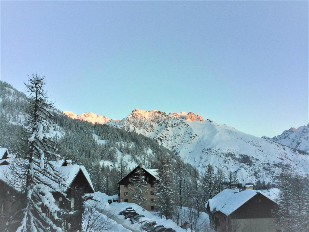 une montagne enneigée avec un bâtiment et des bâtiments enneigés dans l'établissement PUY SAINT VINCENT APPARTEMENT T2 BALCON SUPER PANORAMA AVEC PARKING PRIVE COUVERT et PISCINE L'ETE, à Puy-Saint-Vincent