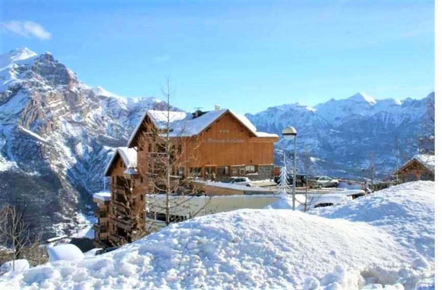 une maison enneigée sur une montagne avec des montagnes dans l'établissement PUY SAINT VINCENT APPARTEMENT T2 BALCON SUPER PANORAMA AVEC PARKING PRIVE COUVERT et PISCINE L'ETE, à Puy-Saint-Vincent