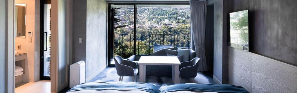 - une chambre avec une table, des chaises et une grande fenêtre dans l'établissement HAKONE NICA, à Hakone 37 autres photos