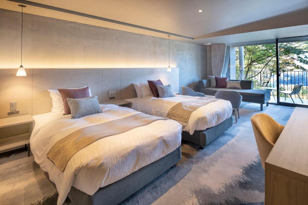 - une chambre avec deux lits, un canapé et une chaise dans l'établissement HAKONE NICA, à Hakone