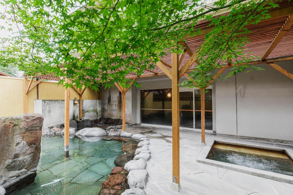 un jardin avec un étang et des arbres devant un bâtiment dans l'établissement Yufuin Kotobuki Hananosho, à Yufu